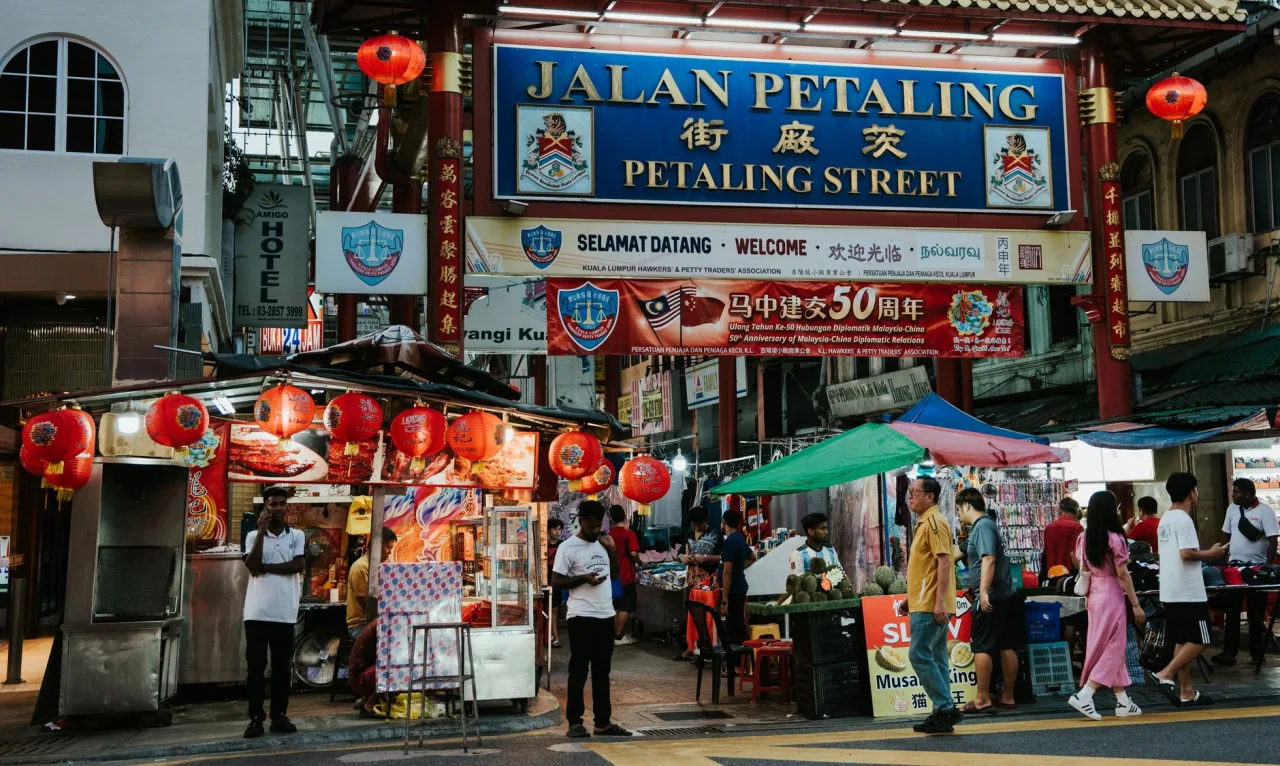 Stalls and shoppers beneath the Jalan Petaling gateway in Kuala Lumpur's Chinatown.