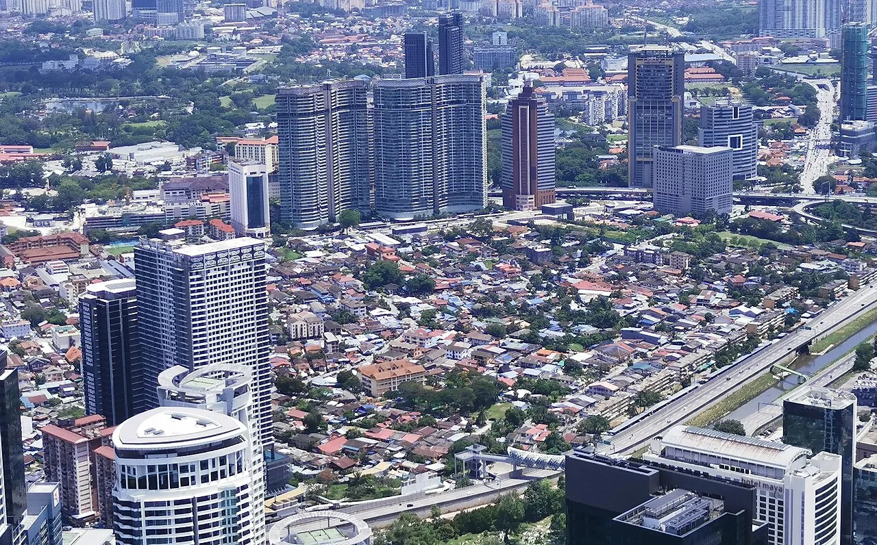 Aerial view over Kampung Baru's low-rise neighbourhood toward the city.