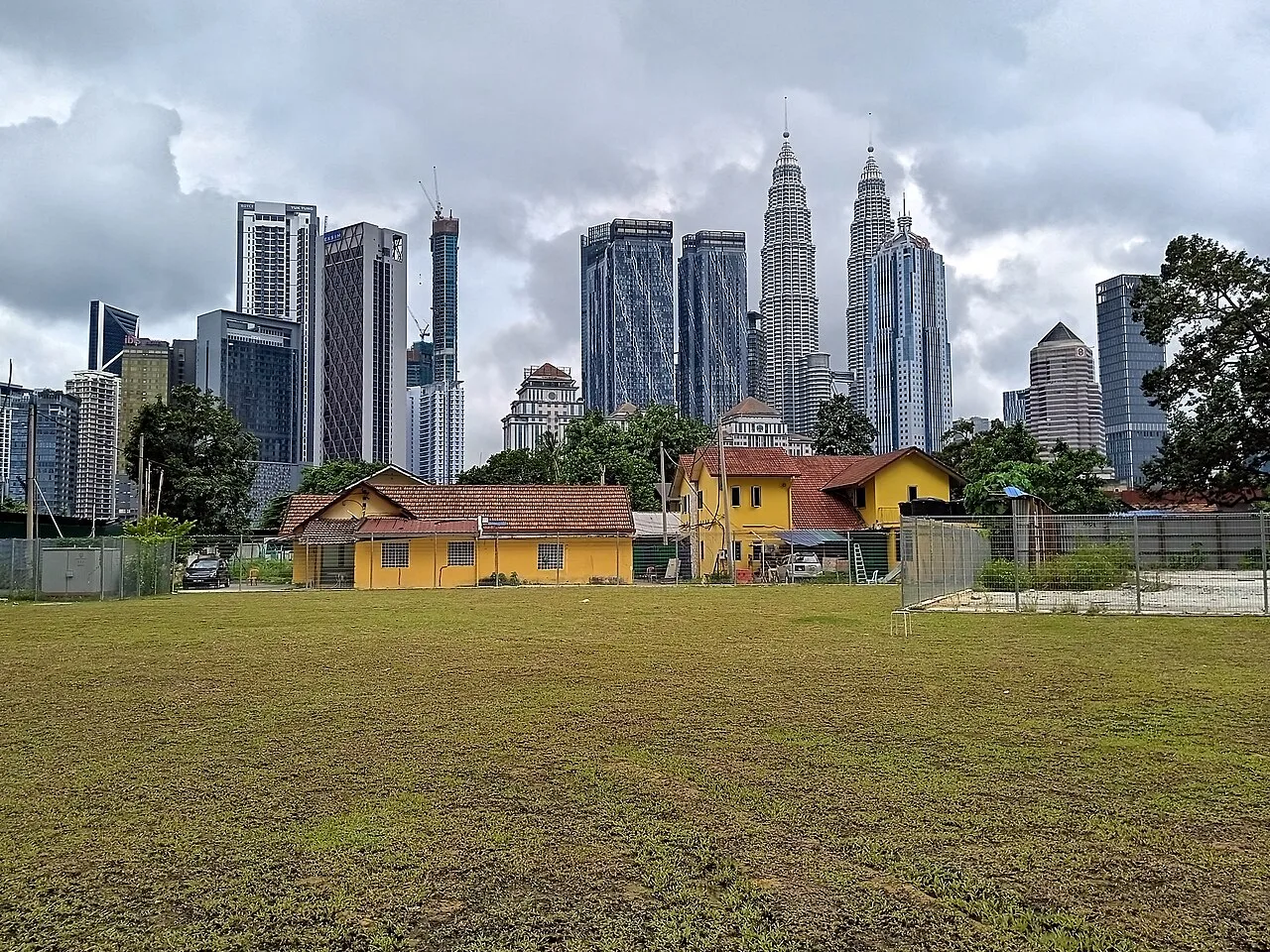 Traditional Kampung Baru buildings beneath Kuala Lumpur's modern skyline.